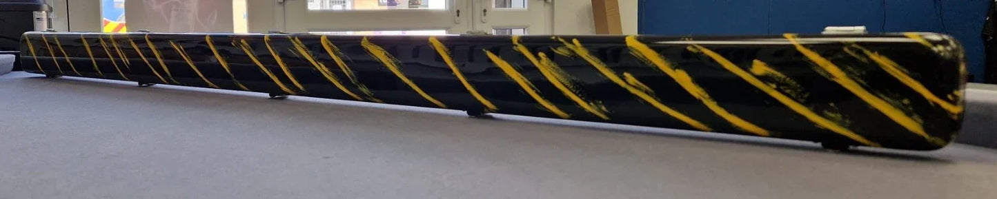 Black safety barrier with yellow diagonal stripes on indoor grey surface