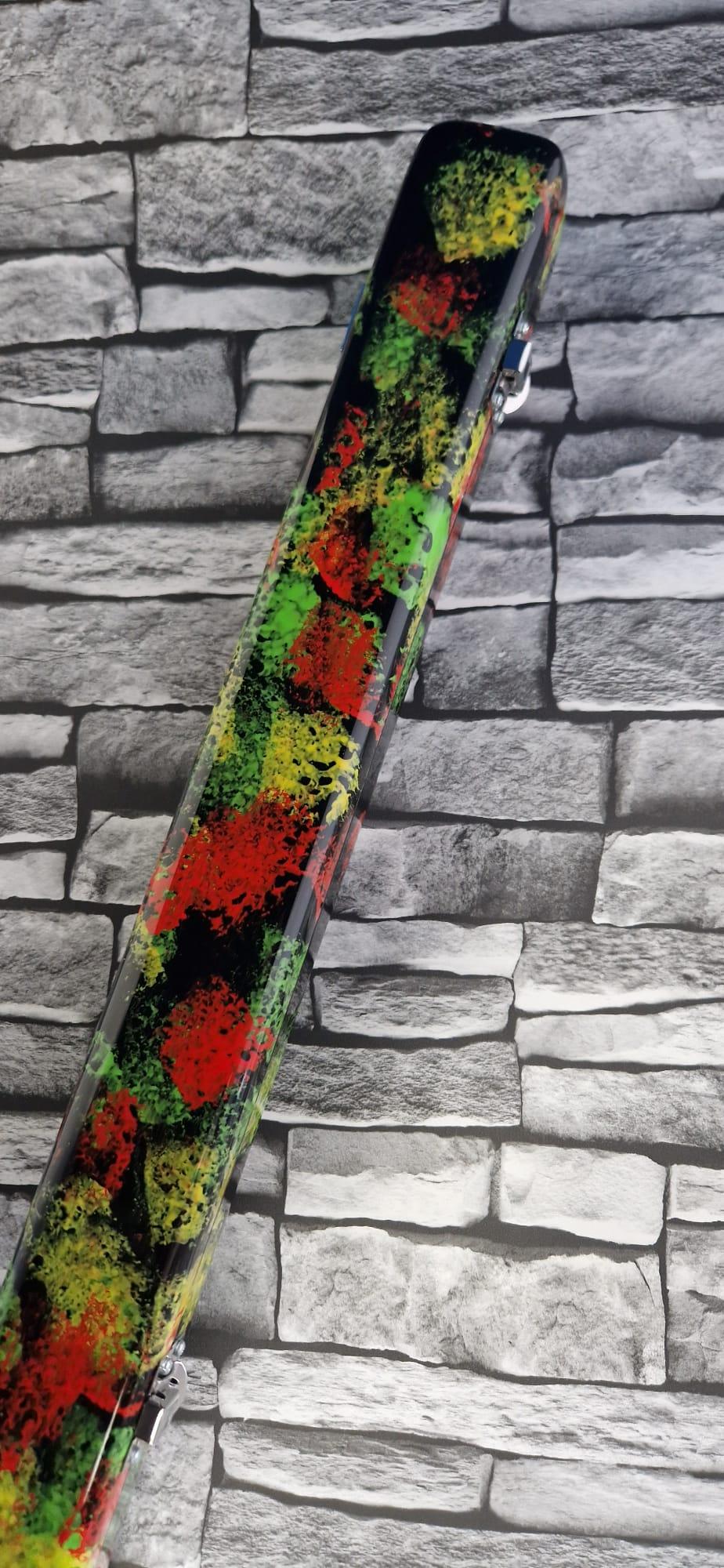 Colorful splatter-painted hard case with red, green, and yellow on stone brick background