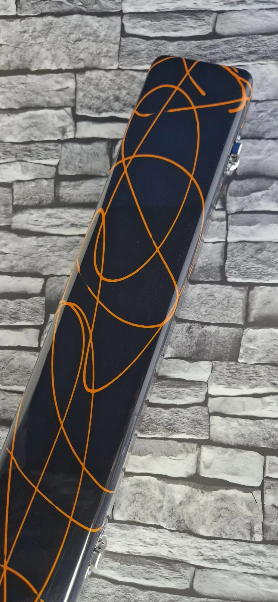 black hard case with orange abstract lines on stone brick background