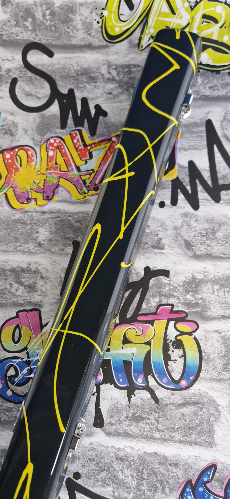 Black bike frame with yellow graffiti lines on street art brick wall backdrop