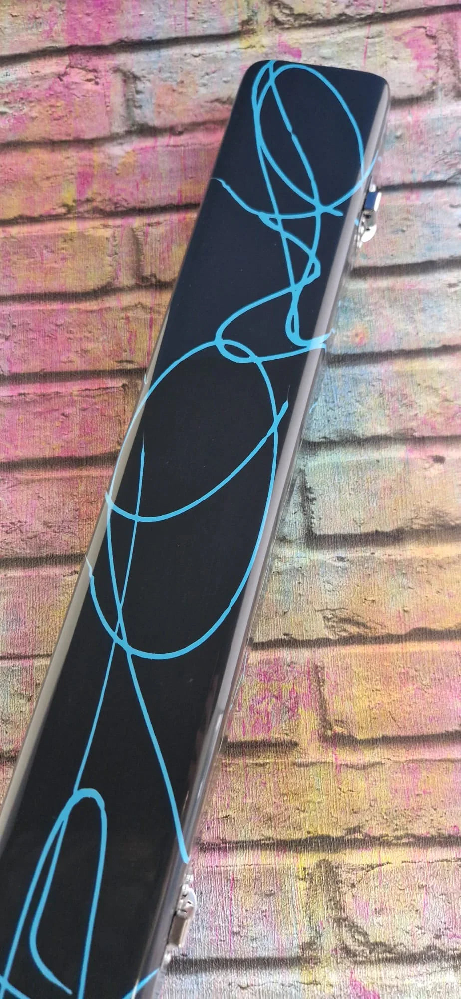 Black rectangular case with blue abstract lines on a colorful brick background